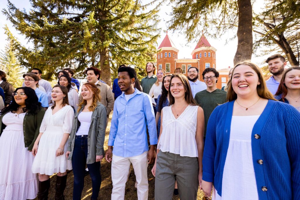N A U's Shrine of the Age's choir performs on a sunny day in front of the Old Main building.
