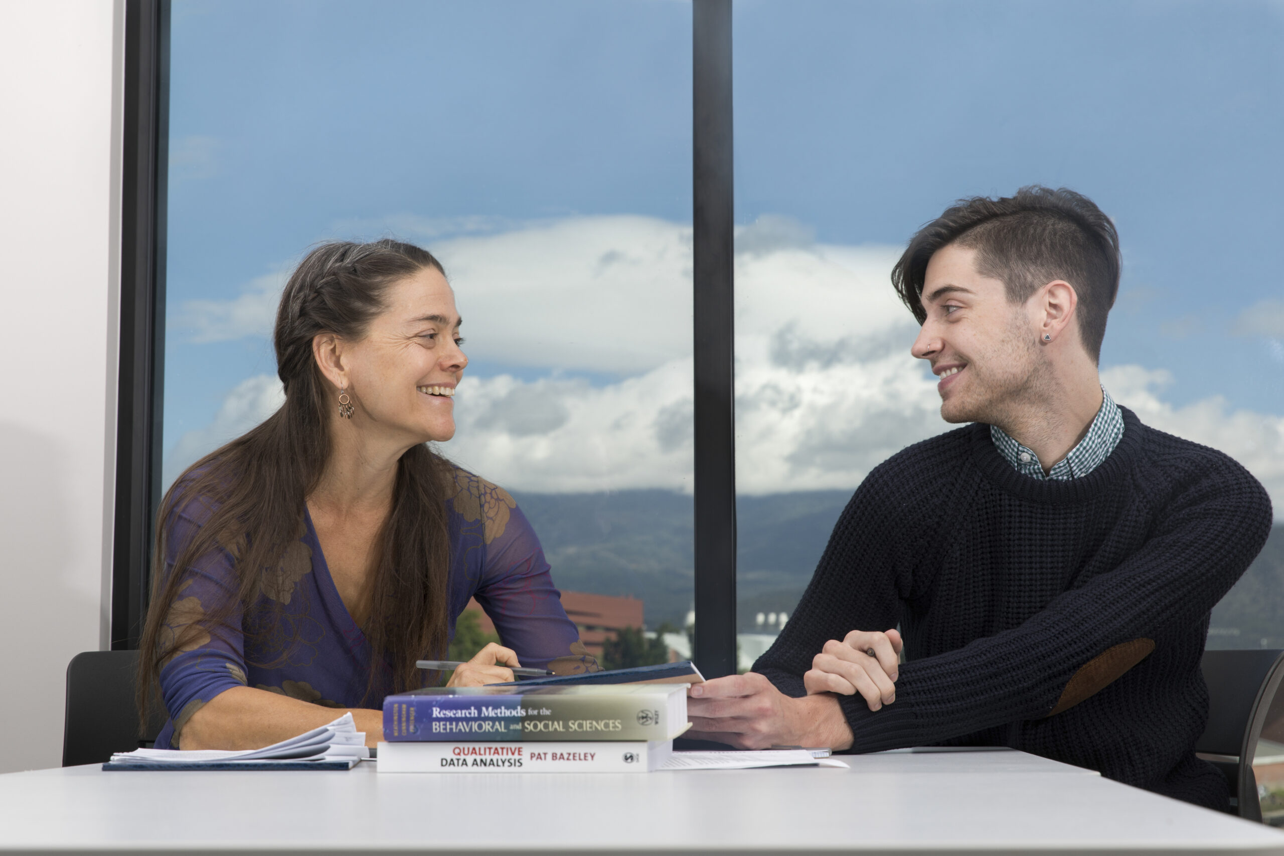 NAU students sit at a table in front of a large window.