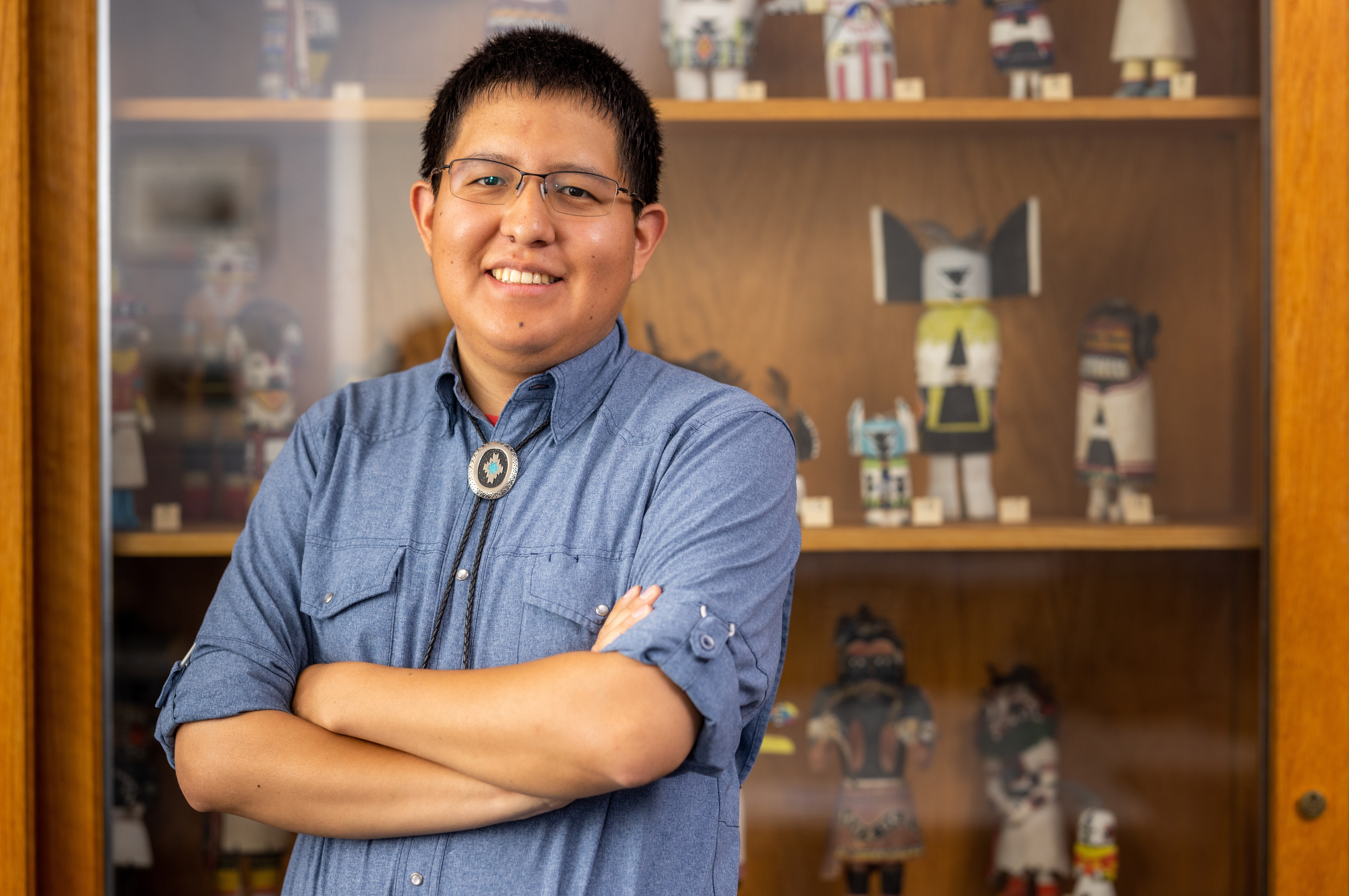 NAU student, Ryan Gilbert, poses in front of indigenous artifacts.