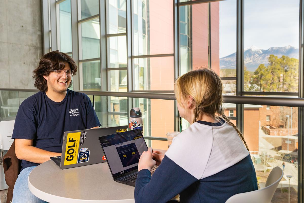Students in the Health and Sciences building studying together with the snow-covered San Francisco Peaks in the background.